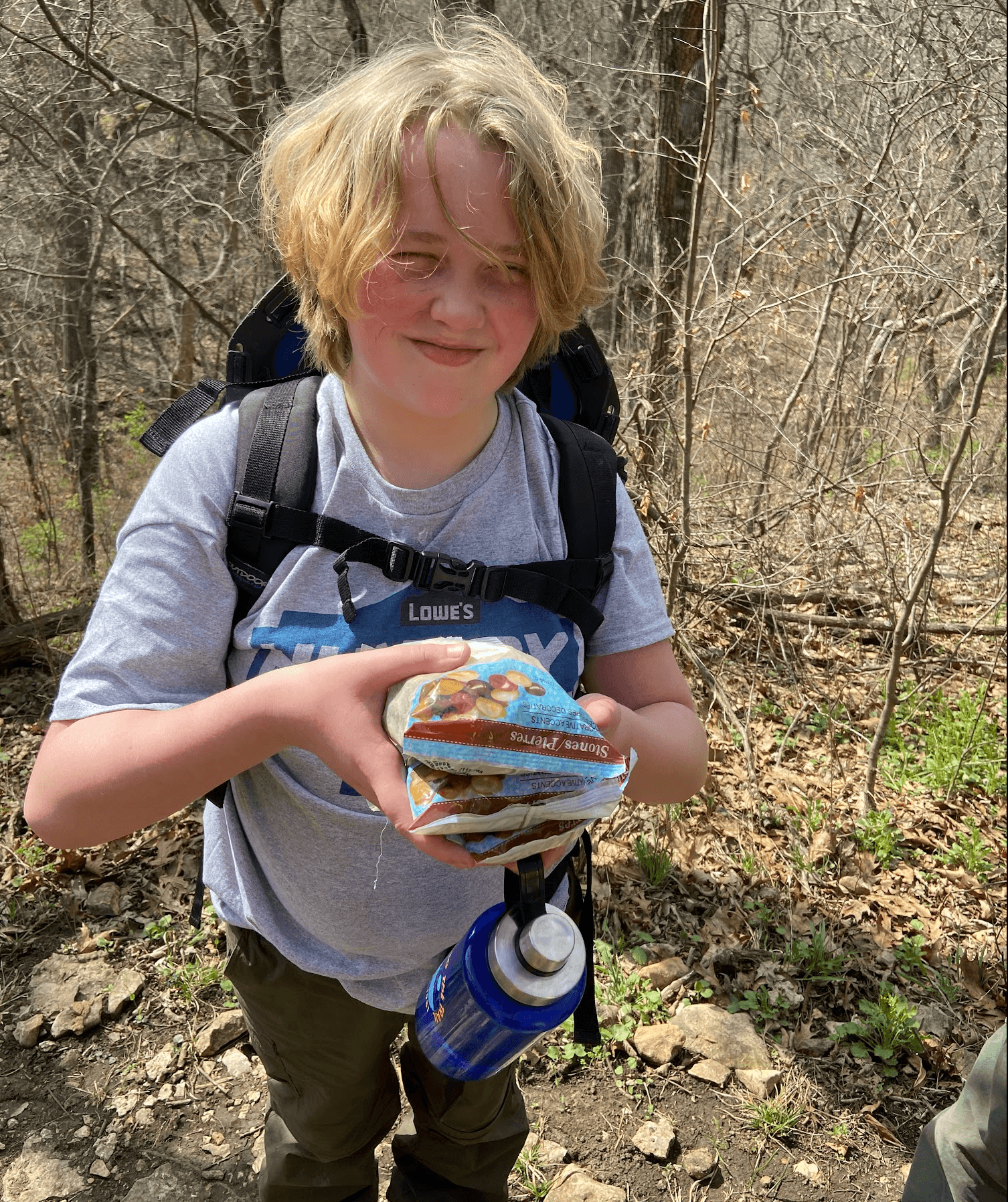Youth holding rocks to weigh down backpacking pack.